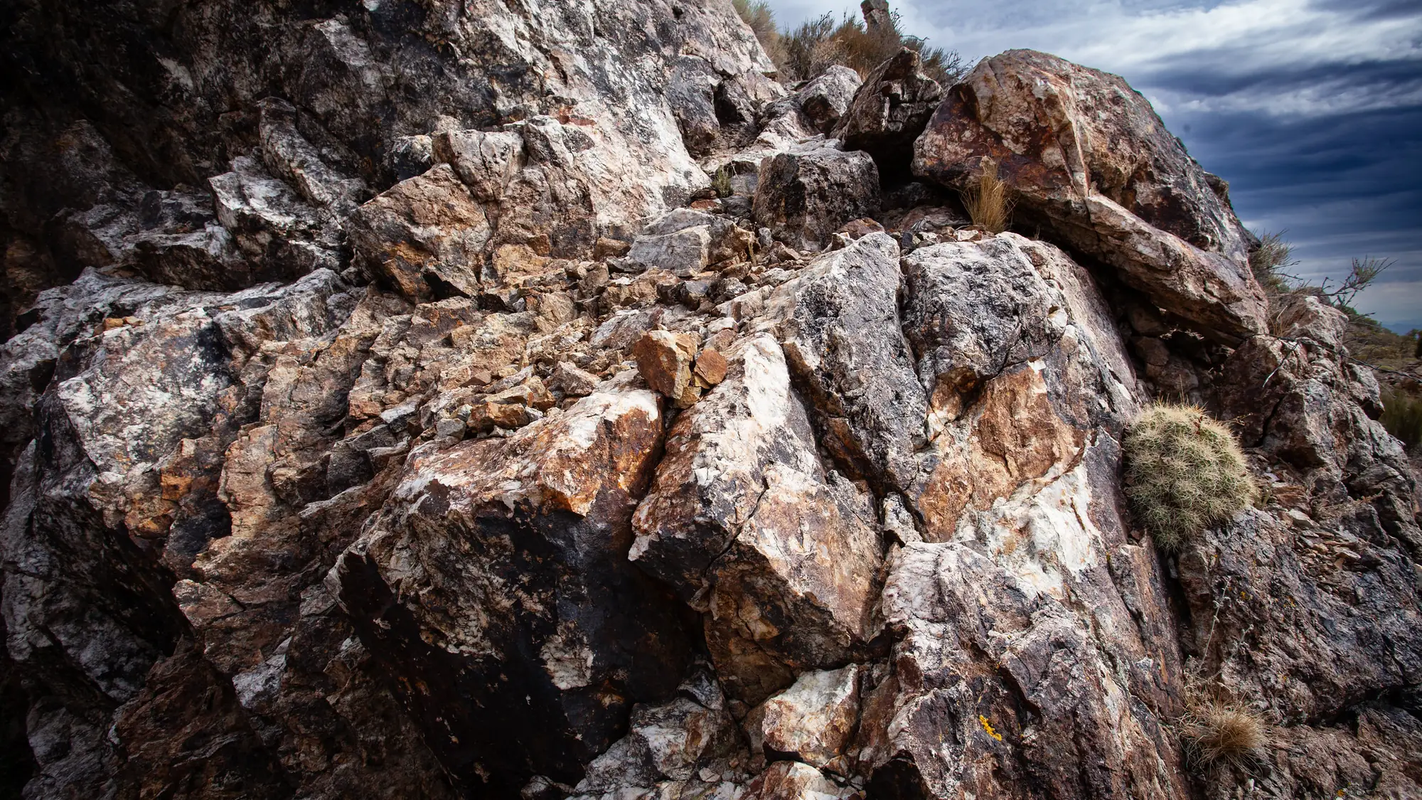 A close view of a quartz-veined rock outcrop under a dark sky